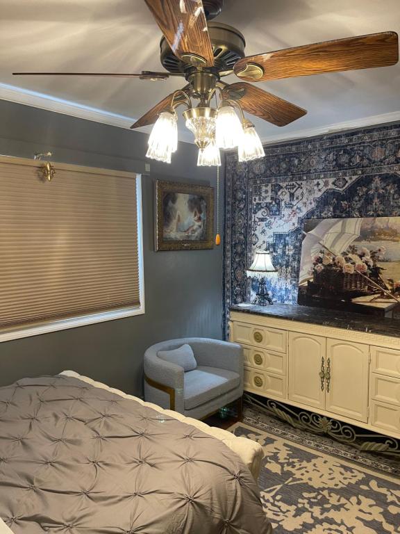 Schlafzimmer mit einem Deckenventilator, einem Bett und einem Stuhl in der Unterkunft Splendid Room in House 10 mins to Airport in Saint Louis