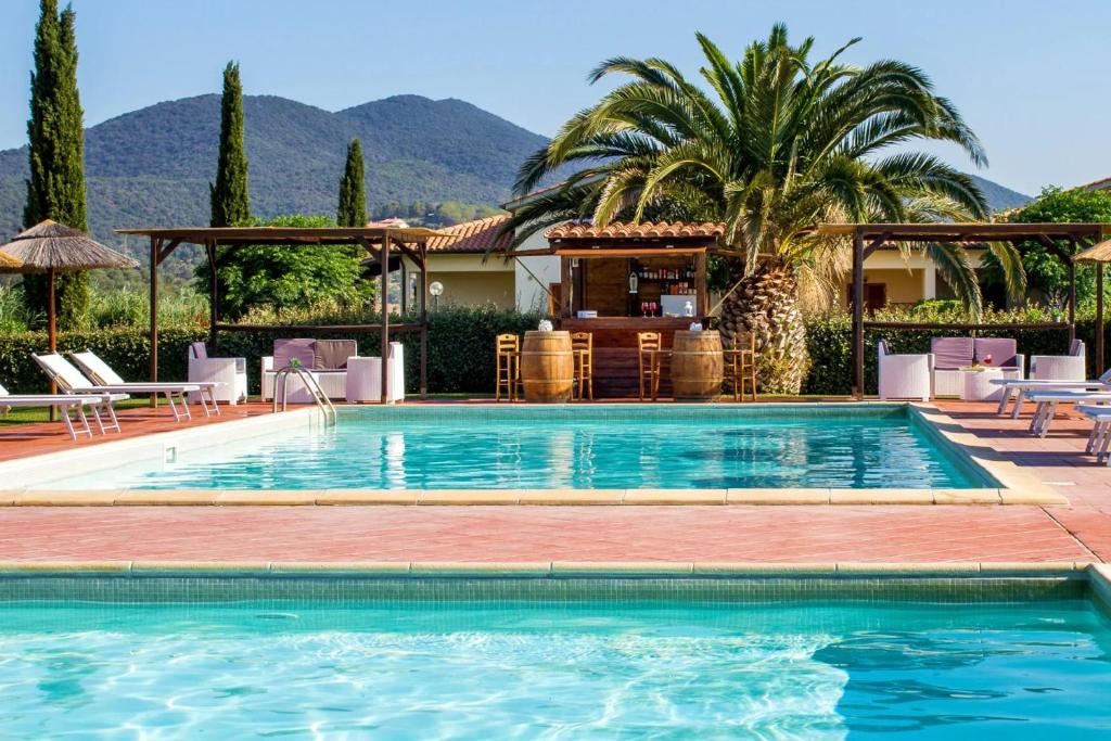 une piscine avec des chaises et une maison dans l'établissement Residence Cernaia - Private Cottage, à Castiglione della Pescaia