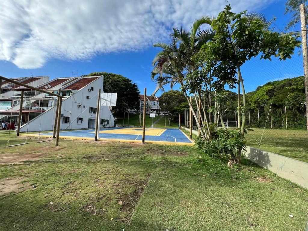ein Tennisplatz mit einer Palme neben einem Gebäude in der Unterkunft Bela Vista Condominio Village dos Pássaros in Guarapari