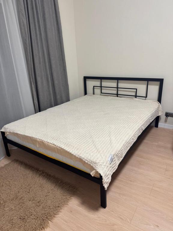 un letto con struttura nera e materasso bianco di Квартира a Dnipro