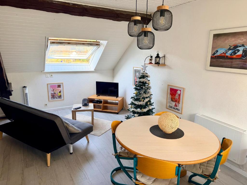 a living room with a table and a christmas tree at Charmant studio à Saulcy-sur-Meurthe, Vosges in Saulcy-sur-Meurthe