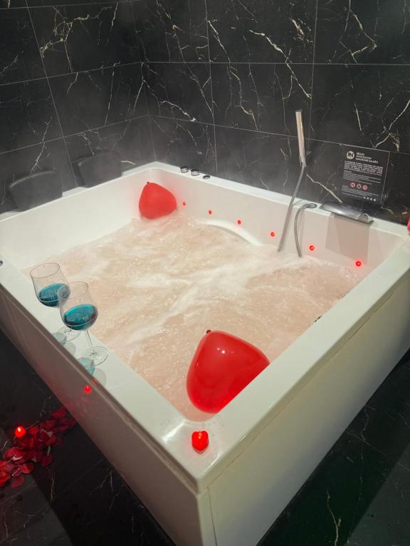 a bathtub with a red chair and glasses in it at tour des étoiles love room in Trévoux