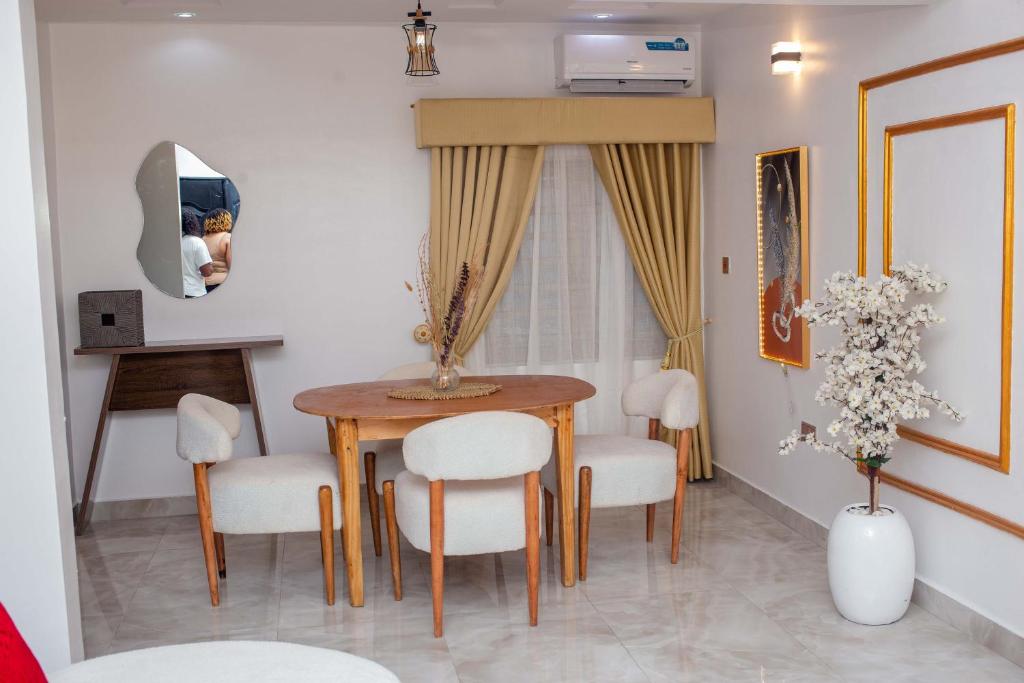 a dining room with a wooden table and white chairs at Little Afrika in Port Harcourt