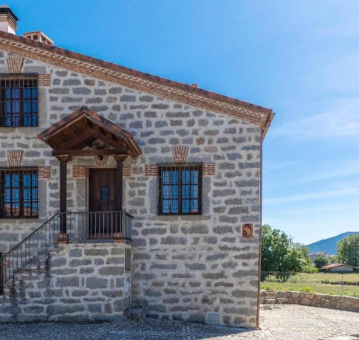 a large stone building with a door and windows at La Bodega de Gredos in Navaluenga
