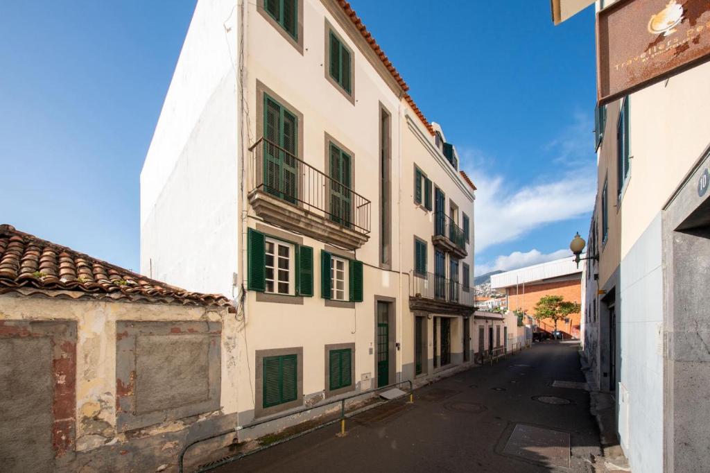 an alley in an old town with green shutters at Sun & Roses in Funchal