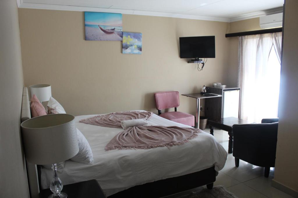 ein Schlafzimmer mit einem Bett mit einer Lampe und einem TV in der Unterkunft Setumishi Royal Lodges in Ellisras