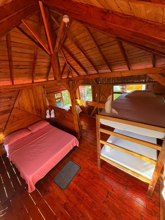 a room with two beds in a wooden cabin at Wila Hostal in Gigante