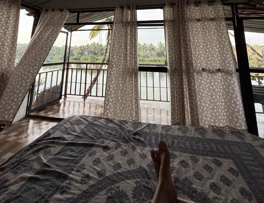 a persons feet on a bed with a view at RivoGoa riverside Homestay in Bardez