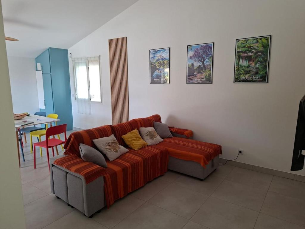 ein Wohnzimmer mit einem roten Sofa und einem Tisch in der Unterkunft Le Victoria - 3 pièces in La Possession