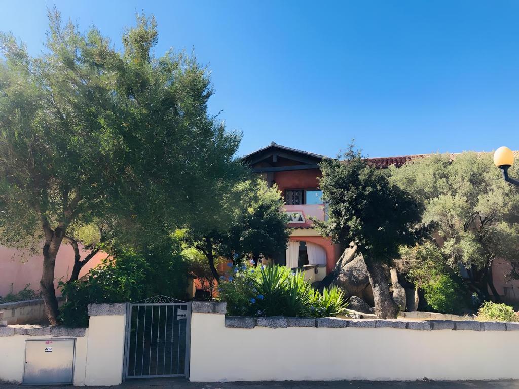 a fence in front of a house with trees at Trilocale I Graniti San Teodoro in Monte Petrosu