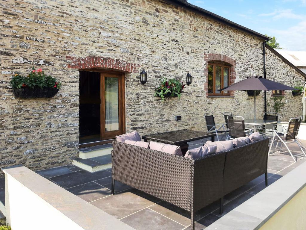 a stone building with a patio with a table and chairs at Slade Barn - Uk42977 in Highbray
