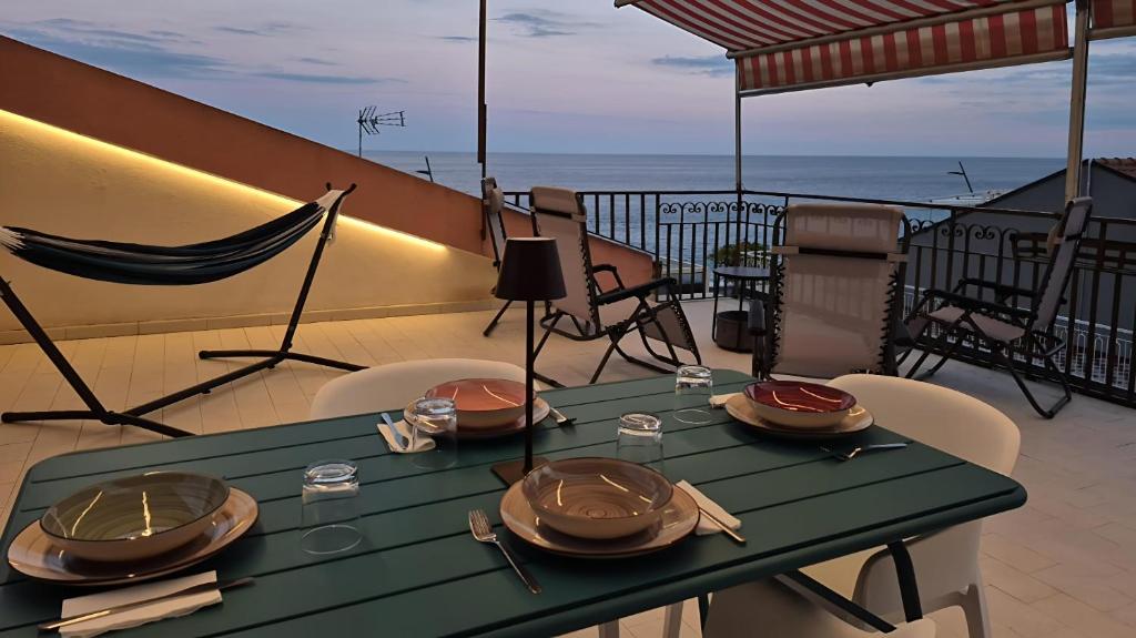 una mesa verde con platos de comida en el balcón en Lumeriam Sea Loft, en Roccalumera