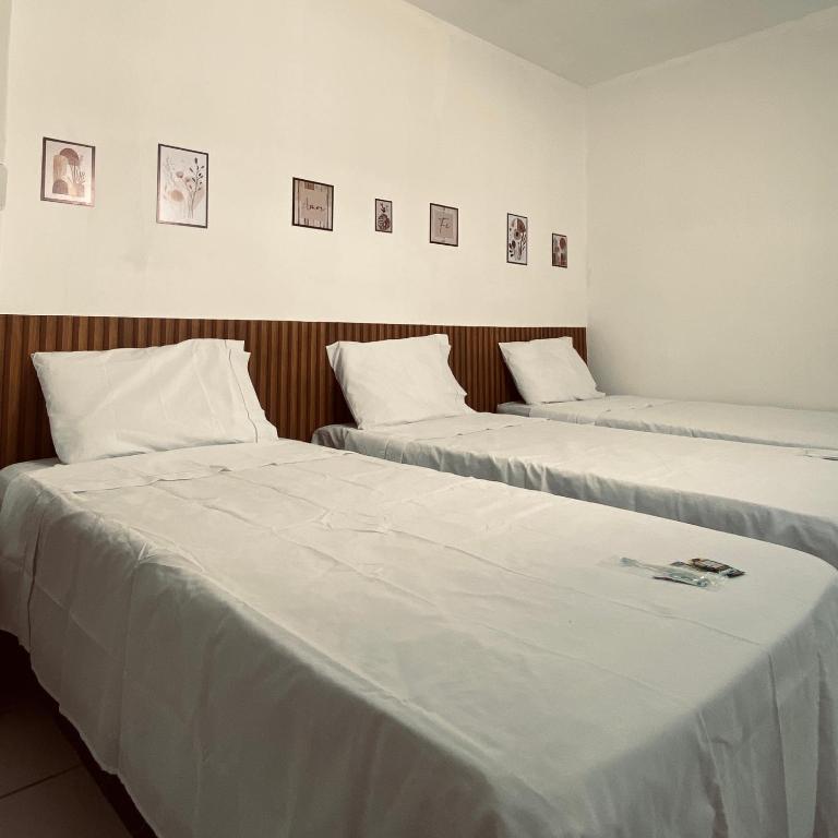 two beds in a room with white sheets at Pousada Central in Buíque