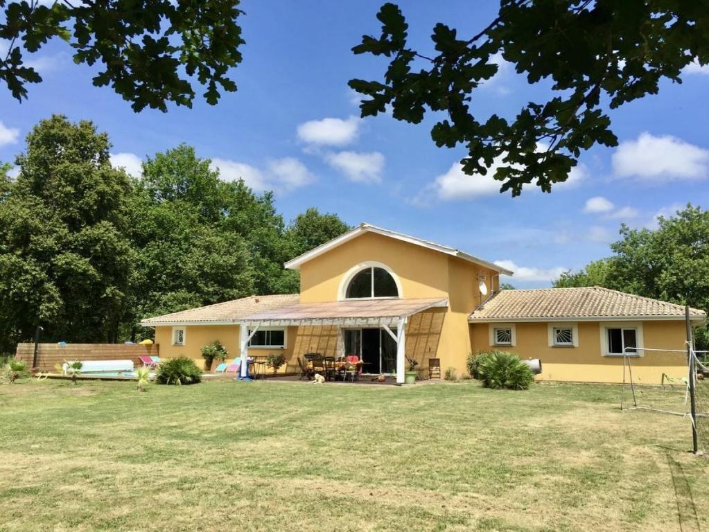una gran casa amarilla con un gran patio en VillasHomeClet - Villa Côte & Lac, en Naujac-sur-Mer