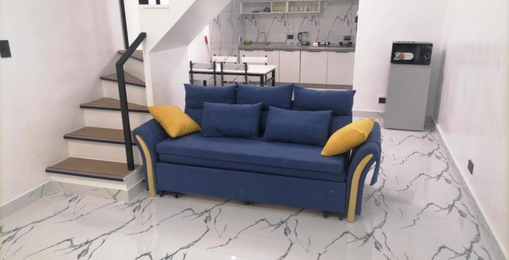 ein blaues Sofa mit gelben Kissen im Wohnzimmer in der Unterkunft Navio Transient House in Cabuyao