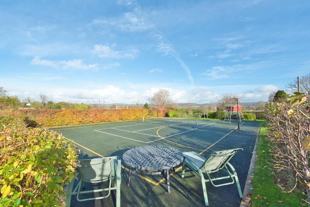 a tennis court with a table and chairs on it at Magnificent Getaway - Tennis, Climbing & More! in Backwell
