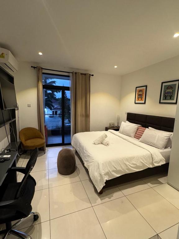 a bedroom with a bed and a desk and a chair at Luxury Sid Apartments in Accra