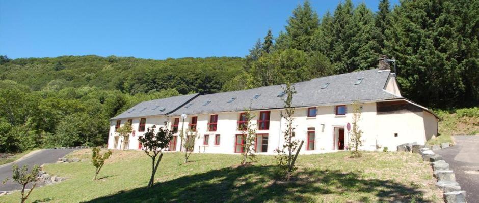 a large white building with red windows in a field at Gîte de la Borie de Pourtou in Condat