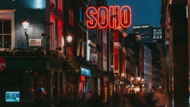 een stadsstraat 's nachts met een neonbord bij London Grand in Londen