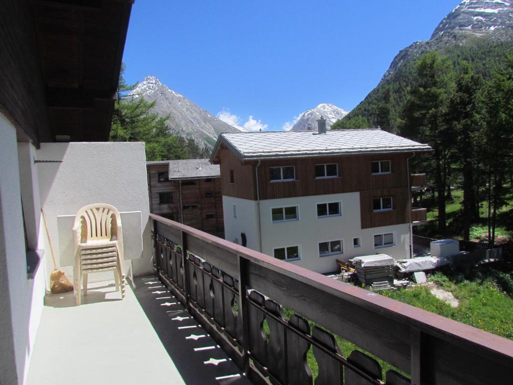 a chair on a balcony with a view of a building at Haus Alfa in Saas-Fee