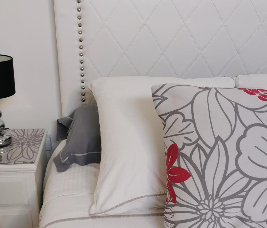 a bedroom with a white bed with a flower pillow at Studios MISTRAL21 en Camargue in Salin-de-Giraud