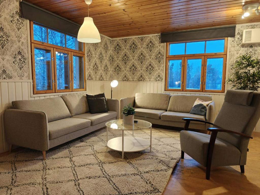 un soggiorno con divani, tavolo e finestre di Spacious Apartment for 12 with Sauna a Laitasaari
