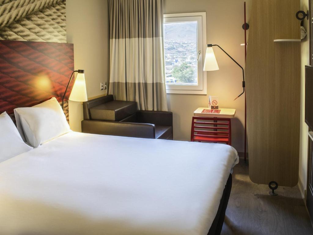Una habitación de hotel con una cama, una silla y una ventana. en ibis Copiapo, en Copiapó