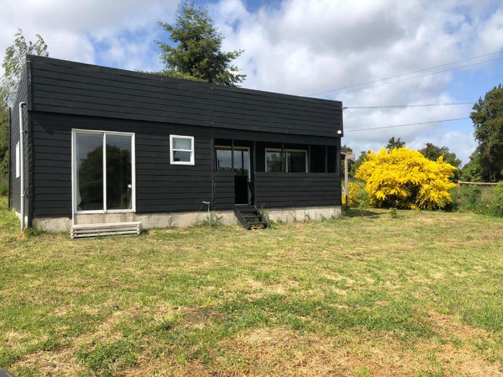 une maison noire avec une grande cour devant elle dans l'établissement Casa en Frutillar, à Frutillar