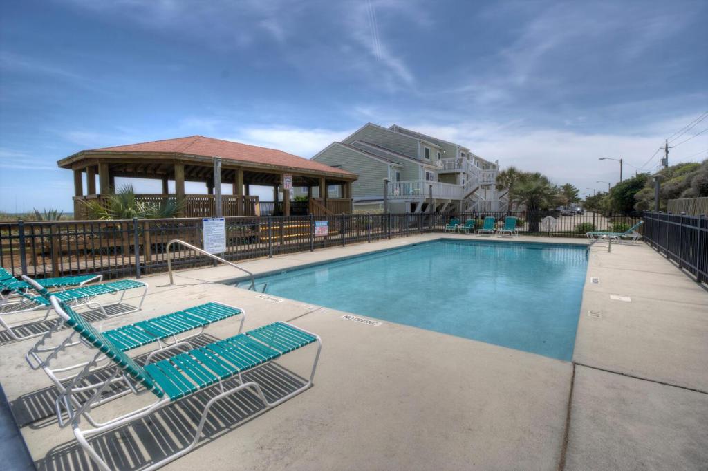 a swimming pool with lounge chairs and a gazebo at Three Little Birds in Kure Beach