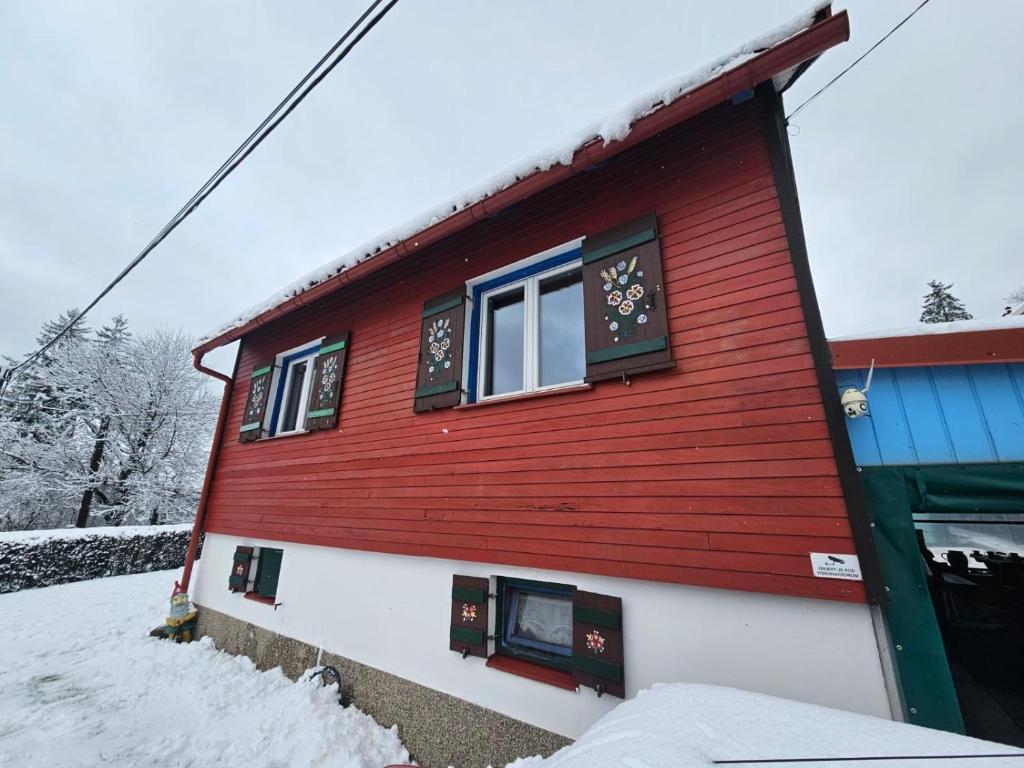 ein rotes und weißes Haus mit Schnee drauf in der Unterkunft Kuća Šarenka in Kupjak