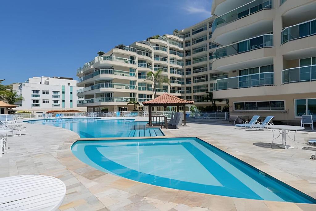 a swimming pool with a large apartment building in the background at Apart hotel a Beira Mar na praia do Recreio in Rio de Janeiro