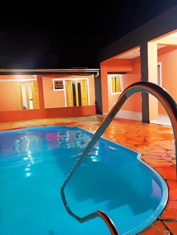 a large swimming pool with a hose in front of a house at Casa Recanto de Brotas suítes para família e grupos de amigos in Brotas