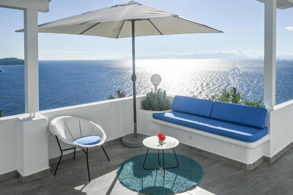 a balcony with a blue couch and a table and an umbrella at Mediterranean Beauty in Skiathos