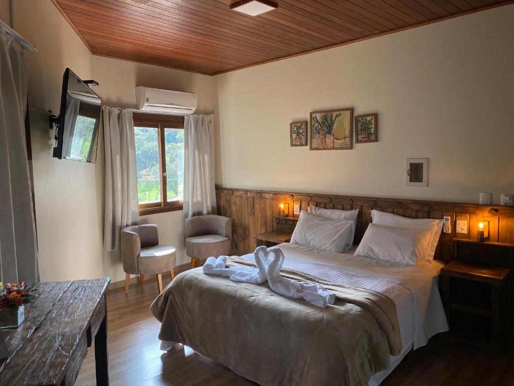 ein Schlafzimmer mit einem Bett und einem Tisch und einem Fenster in der Unterkunft Hilltop Chalés Gramado in Gramado