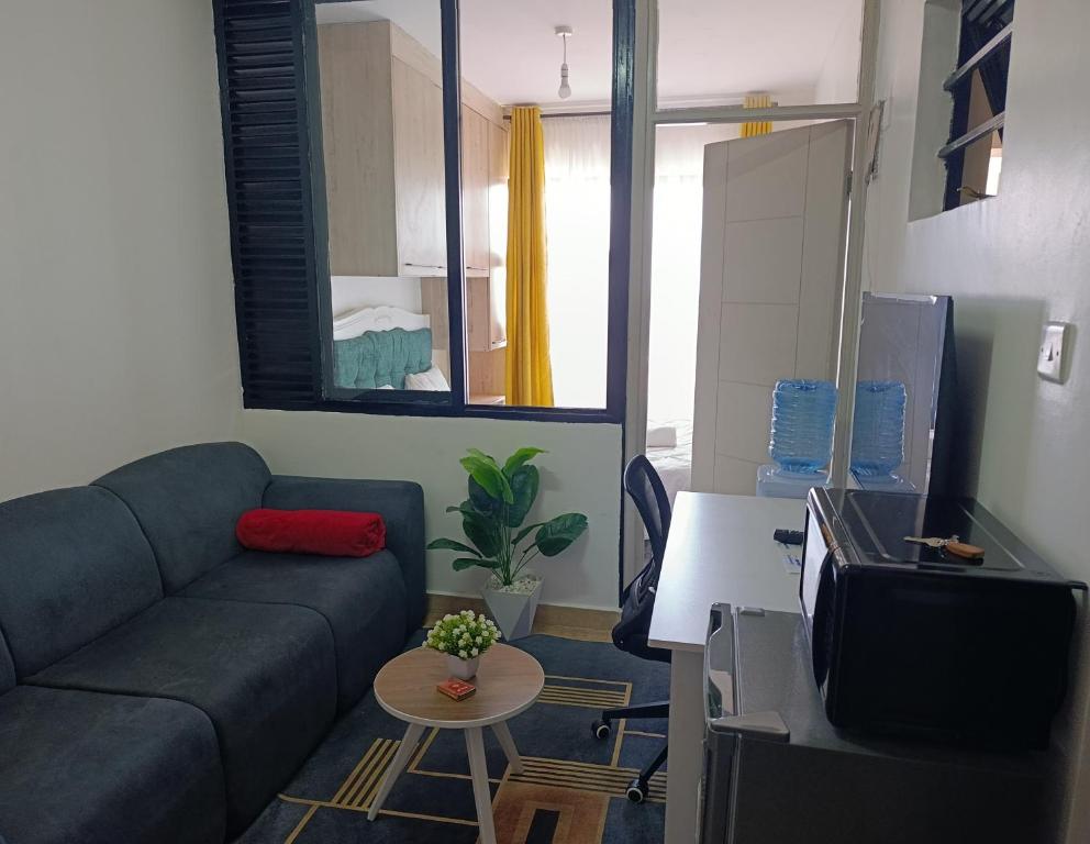 een woonkamer met een bank en een tv bij Executive Studio Kinoo in Rungiri
