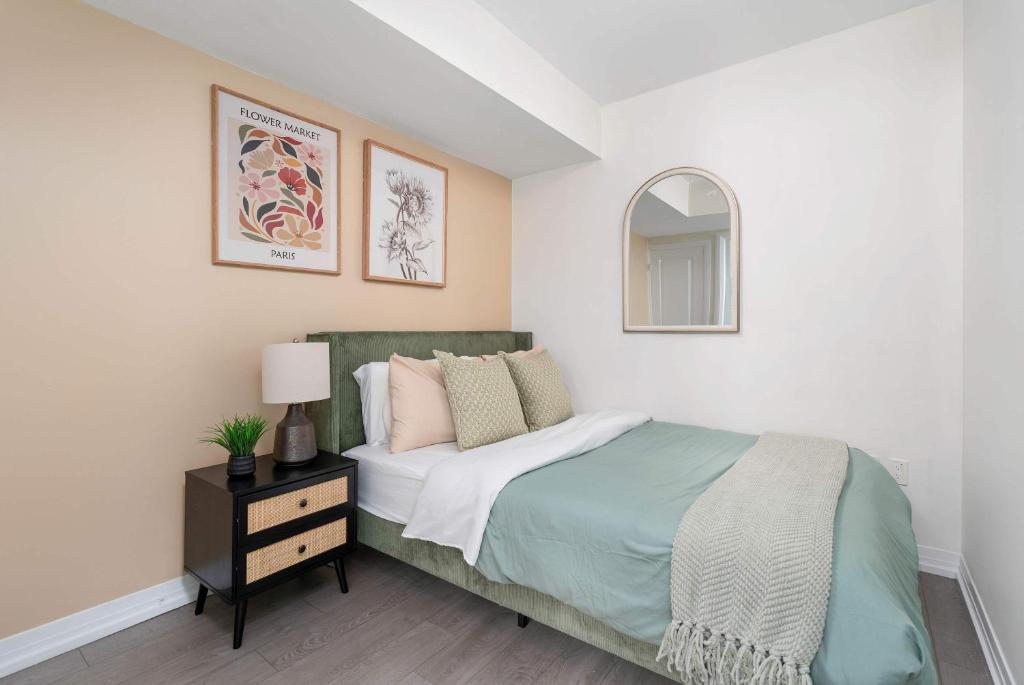 ein weißes Schlafzimmer mit einem Bett und einem Spiegel in der Unterkunft Chic 2BR Condo Toronto Core Steps to Eaton Centre in Toronto