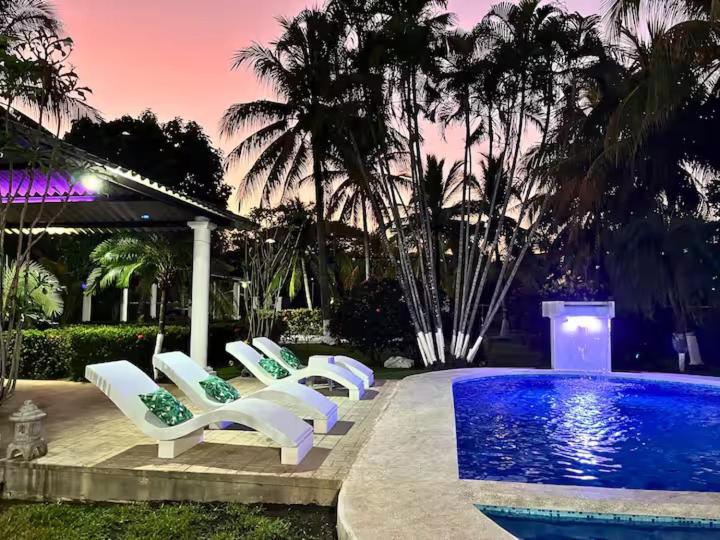 eine Gruppe weißer Liegestühle neben einem Pool in der Unterkunft Pool • Game Room • Fire Pit • Resort Access in Los Cóbanos