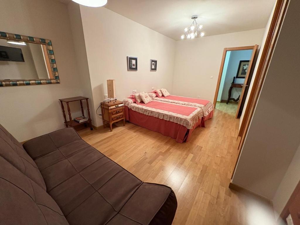 a bedroom with a bed and a couch and a mirror at Portosín beach apartment in Goyanes