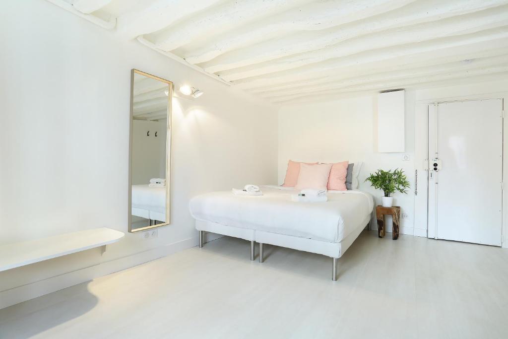 une chambre blanche avec un lit et un miroir dans l'établissement Rent a Room - Studio Bonne Nouvelle, à Paris