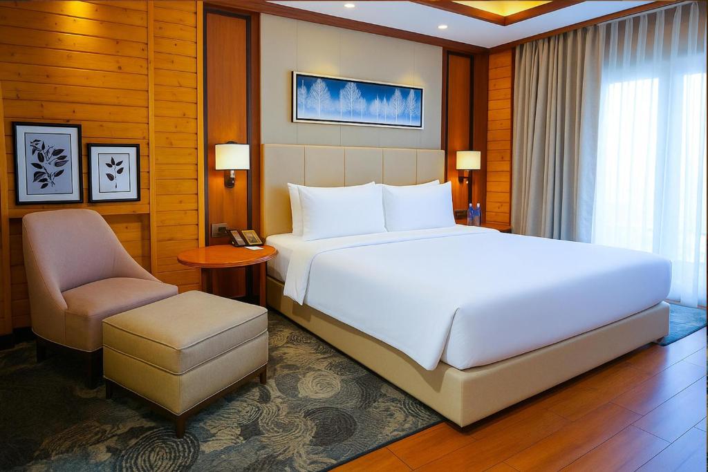 een slaapkamer met een groot wit bed en een stoel bij Radisson Blu Resort Dharamshala in Dharamshala