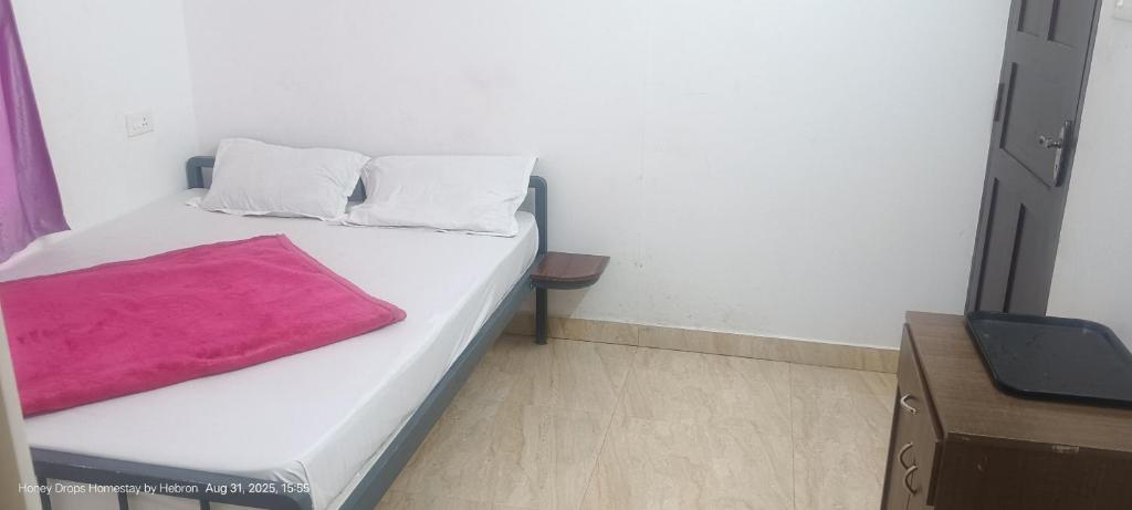 Un dormitorio con una cama con una manta rosa encima. en Honey Drops Homestay by Hebron, en Kanthalloor