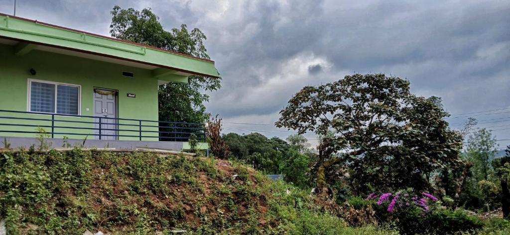 ein grünes Haus mit Balkon auf einem Hügel in der Unterkunft The Town Cascade in Madikeri