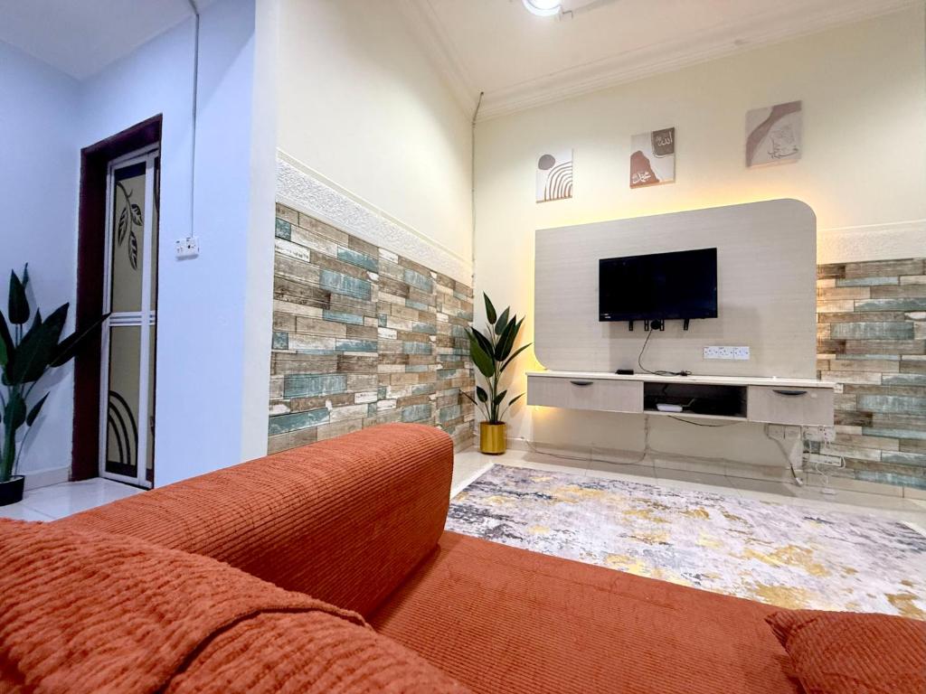 ein Wohnzimmer mit Couch und Flachbildfernseher in der Unterkunft Misty Haven Homestay - Bungalow in Kuala Terengganu