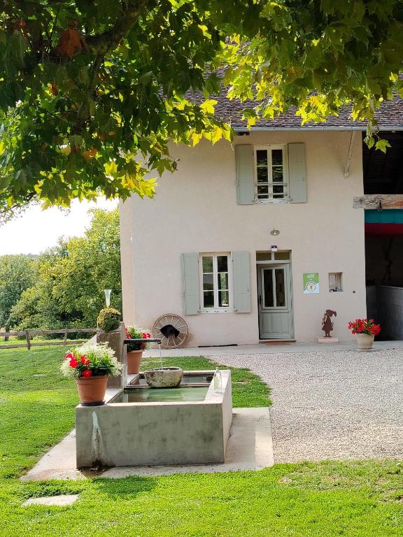 a house with a fountain in front of it at Gîte Le Vieux Chêne in Lhuis