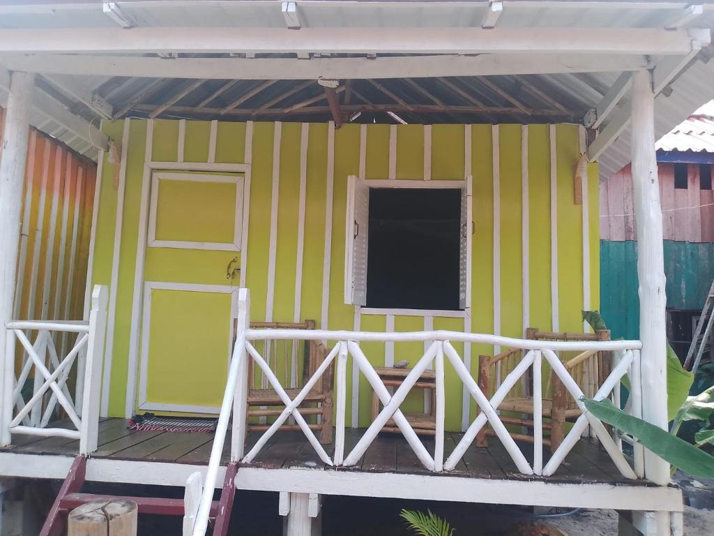 a small house with a green and yellow wall at The Two Tigers - Sok San Village in Phumĭ Kaôh Rŏng