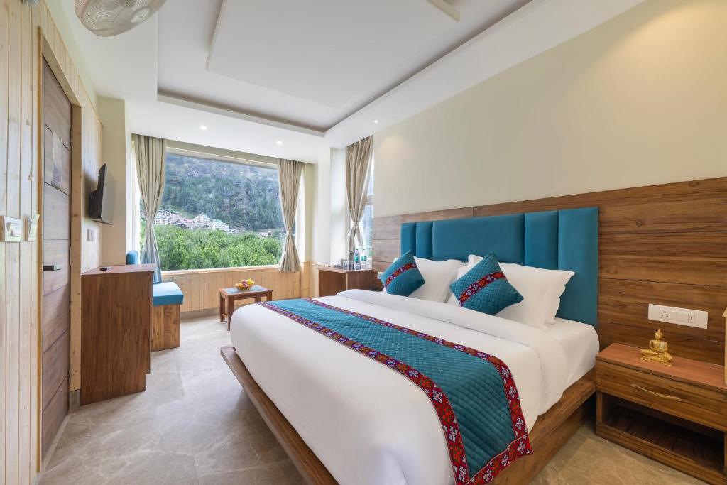 ein Schlafzimmer mit einem großen Bett und einem großen Fenster in der Unterkunft The Ravasa in Manali