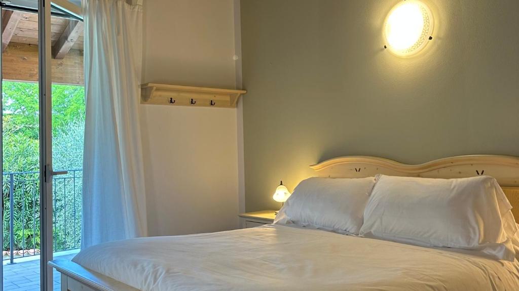 een slaapkamer met een bed met witte lakens en een raam bij Locanda Arizona in Bardolino