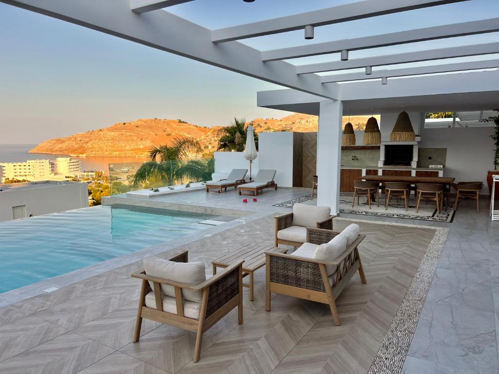 a villa with a swimming pool with chairs and a table at Villa Aristoteles in Líndos