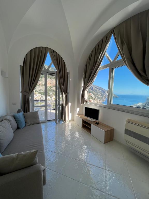 ein Wohnzimmer mit einem Sofa und großen Fenstern in der Unterkunft La Positanella - Positano bright apartment in Positano