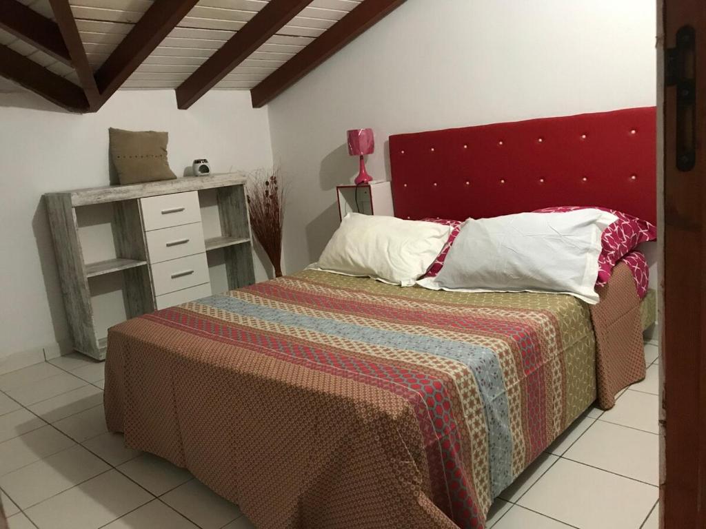 ein Schlafzimmer mit einem Bett mit rotem Kopfteil in der Unterkunft Corail rouge in Sainte-Anne
